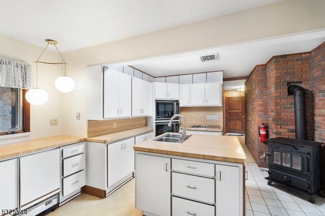 159 US Highway 206, Sandyston Twp, NJ 07826 - kitchen featuring oven, a sink, a wood stove, white cabinetry, and visible vents