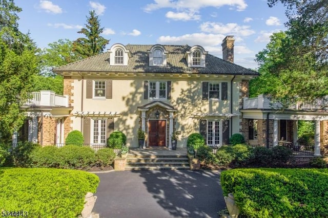 colonial house with stucco siding, french doors, and a chimney