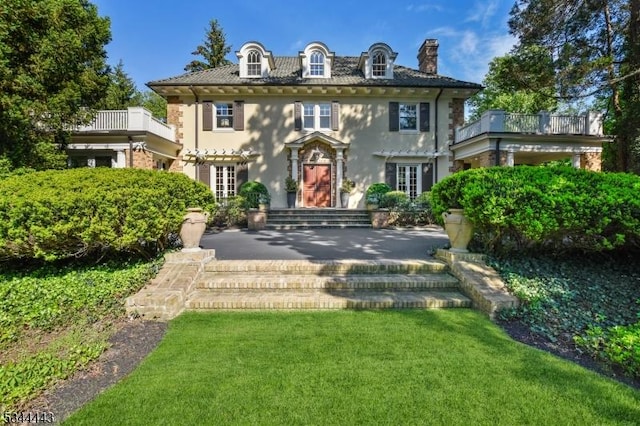 view of front of home with french doors, stucco siding, a chimney, and a front yard