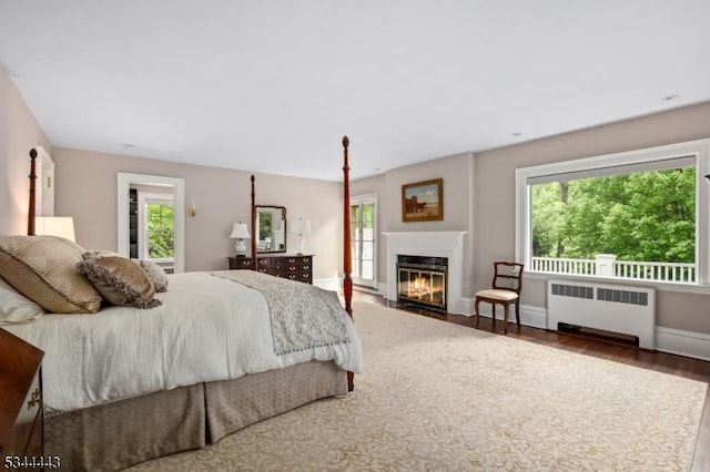bedroom with radiator, wood finished floors, and multiple windows