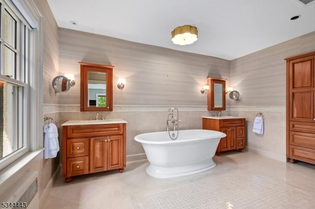 bathroom with a sink, tile patterned flooring, wainscoting, and two vanities