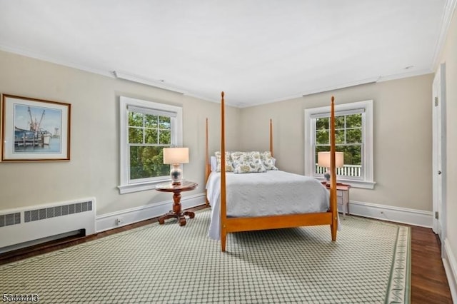 bedroom featuring crown molding, baseboards, wood finished floors, and radiator