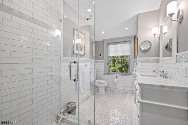full bathroom featuring tile walls, tile patterned flooring, a stall shower, vanity, and toilet