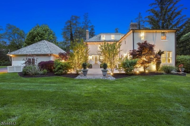 back of property with a yard, a chimney, a patio area, and stucco siding