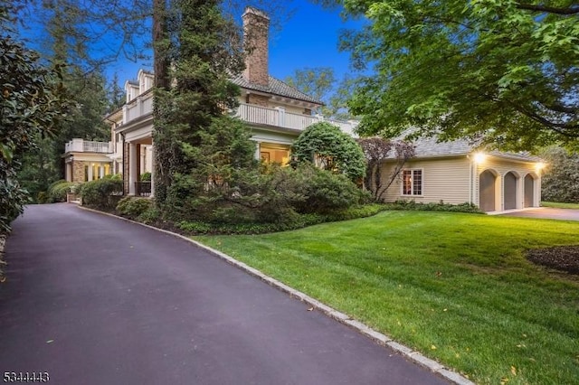 view of front facade featuring a chimney, driveway, and a front yard
