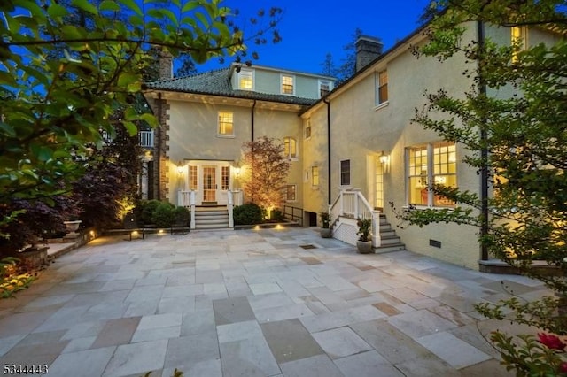rear view of house featuring a patio area, stucco siding, french doors, and a chimney