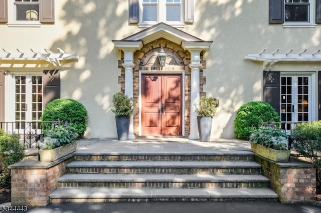 property entrance featuring a pergola, french doors, and stucco siding