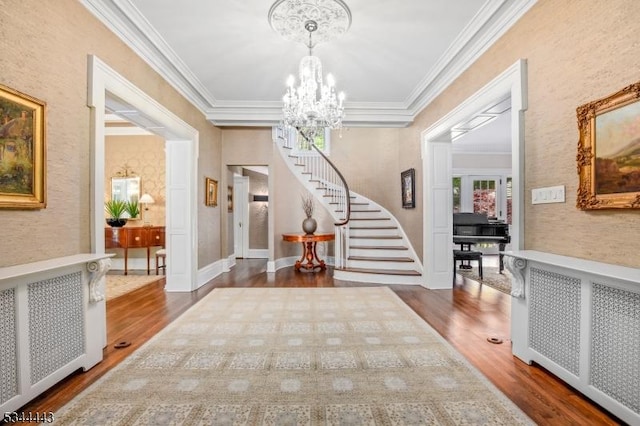foyer featuring crown molding, radiator, wood finished floors, stairway, and a chandelier