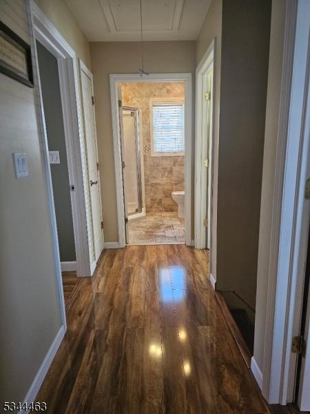 hall featuring attic access, wood finished floors, and baseboards