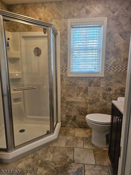 full bathroom featuring vanity, tile walls, a shower stall, and toilet