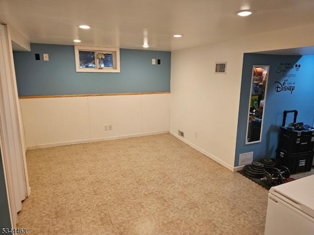 finished basement featuring a wainscoted wall, recessed lighting, and visible vents