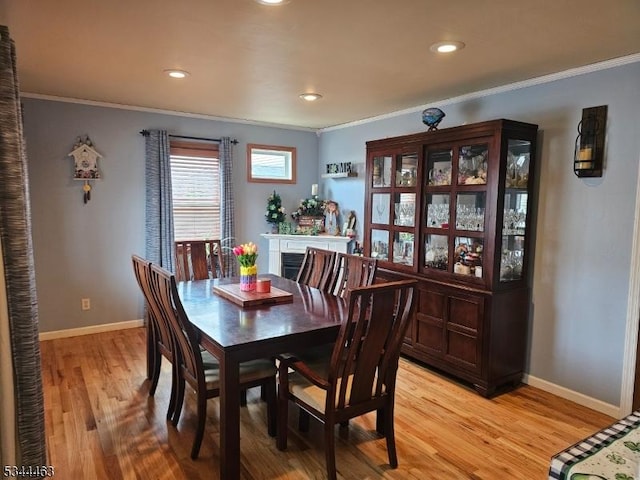 dining room featuring baseboards, light wood-style flooring, and crown molding