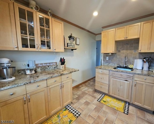 kitchen featuring baseboards, light brown cabinetry, ornamental molding, decorative backsplash, and a sink