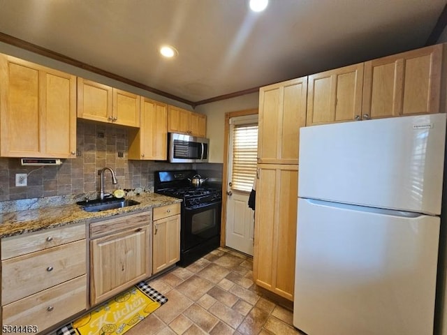 kitchen with light brown cabinetry, a sink, stainless steel microwave, freestanding refrigerator, and black gas range oven