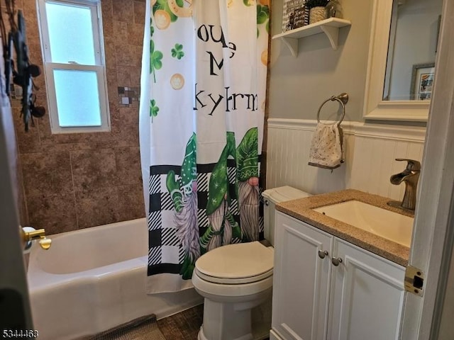 bathroom with a wainscoted wall, shower / bath combo with shower curtain, toilet, and vanity