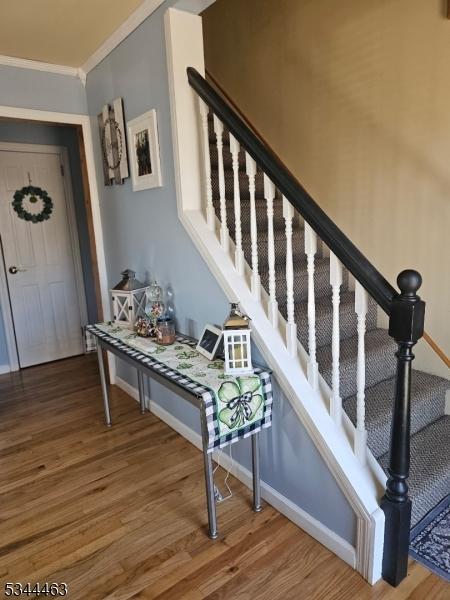 staircase with baseboards, wood finished floors, and ornamental molding