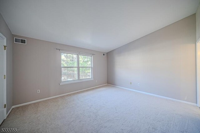 spare room with visible vents, carpet flooring, baseboards, and lofted ceiling
