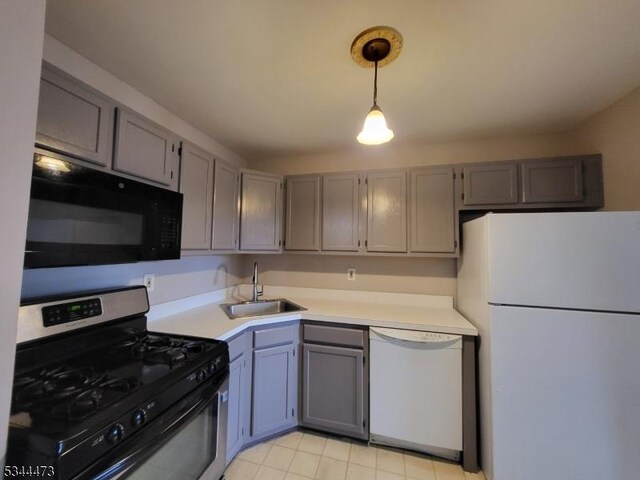 kitchen with gray cabinetry, decorative light fixtures, light countertops, white appliances, and a sink