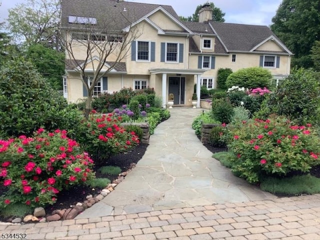 view of front of house with stucco siding and a chimney