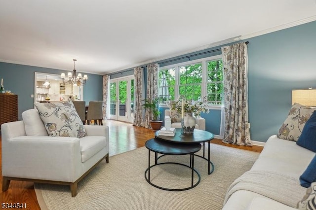 living room featuring crown molding, wood finished floors, a chandelier, and baseboards