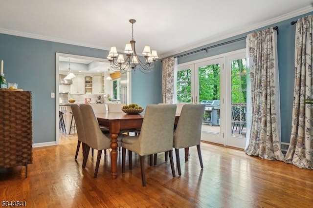 dining space with a chandelier, crown molding, wood finished floors, and baseboards