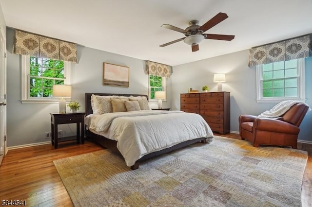 bedroom featuring multiple windows, wood finished floors, and baseboards