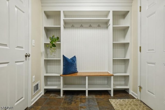 mudroom with baseboards, built in shelves, and stone finish flooring