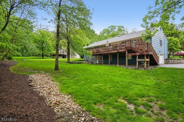 rear view of property with a deck, a yard, a garage, and driveway