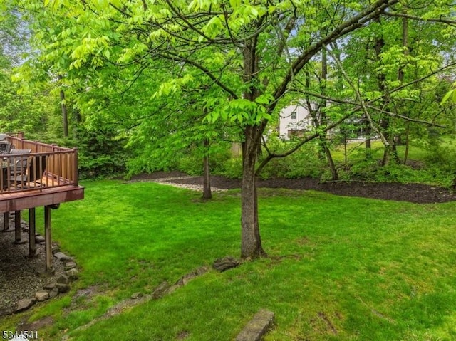 view of green lawn with a wooden deck