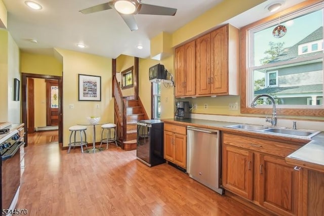 kitchen with dishwasher, beverage cooler, a sink, light wood finished floors, and range