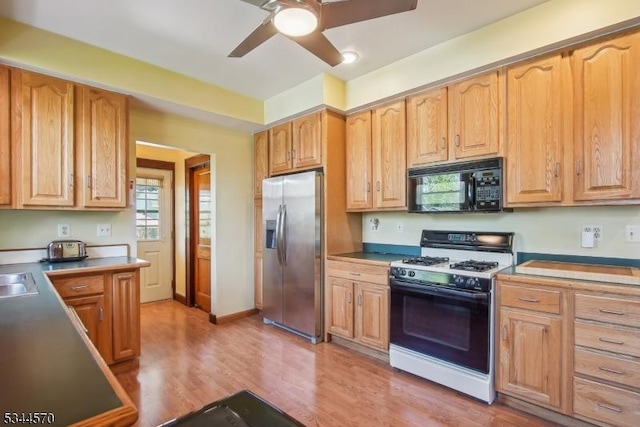 kitchen with ceiling fan, black microwave, stainless steel fridge with ice dispenser, light wood-type flooring, and gas range oven