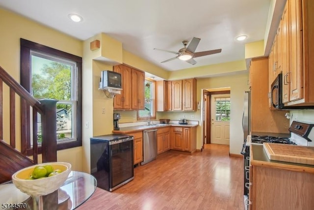 kitchen featuring stainless steel dishwasher, range with gas stovetop, black microwave, plenty of natural light, and a sink