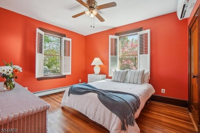bedroom featuring baseboards, a wall mounted AC, baseboard heating, and hardwood / wood-style flooring