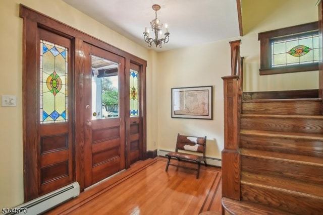 entrance foyer featuring a notable chandelier, stairs, baseboards, wood finished floors, and a baseboard radiator