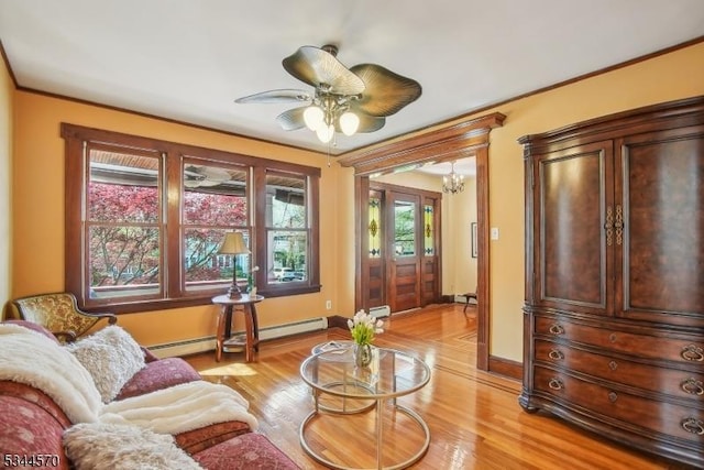 living room with baseboards, a baseboard radiator, ceiling fan with notable chandelier, light wood finished floors, and ornamental molding