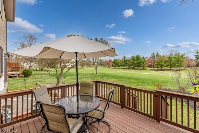 wooden deck with outdoor dining area and a lawn