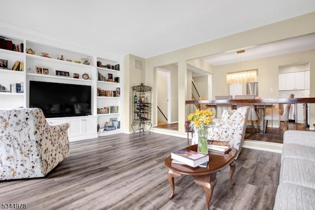 living room with visible vents, a chandelier, wood finished floors, and built in shelves