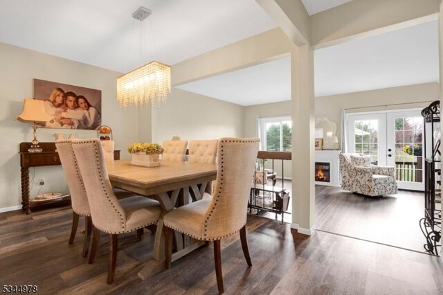 dining room with dark wood-type flooring, baseboards, an inviting chandelier, and a glass covered fireplace