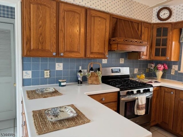 110 Mudtown Rd, Wantage Twp, NJ 07461 - kitchen with stainless steel gas range, premium range hood, brown cabinets, and decorative backsplash