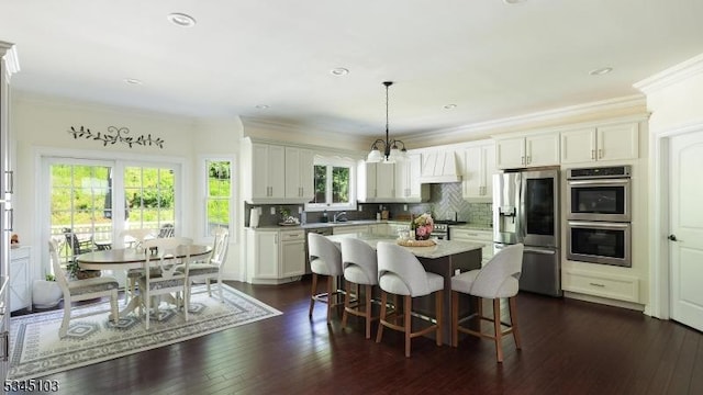 1121 N Washington Ave, Green Brook Twp, NJ 08812 - kitchen featuring appliances with stainless steel finishes, light countertops, a kitchen bar, tasteful backsplash, and crown molding