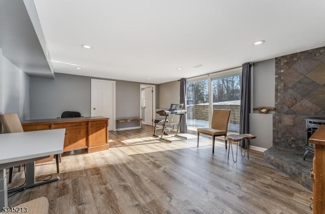 office featuring wood finished floors, recessed lighting, baseboards, and a wood stove