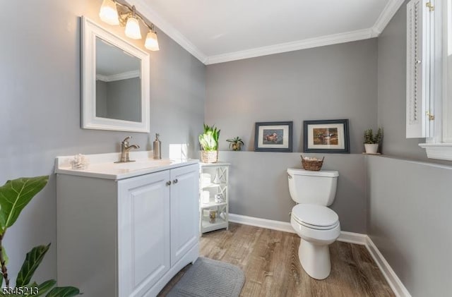 half bath with wood finished floors, toilet, ornamental molding, vanity, and baseboards