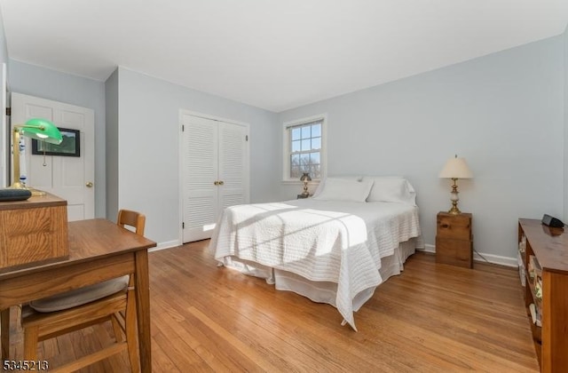 bedroom featuring light wood-type flooring, a closet, and baseboards