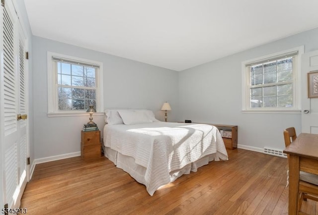 bedroom featuring light wood-style floors, baseboards, and a closet