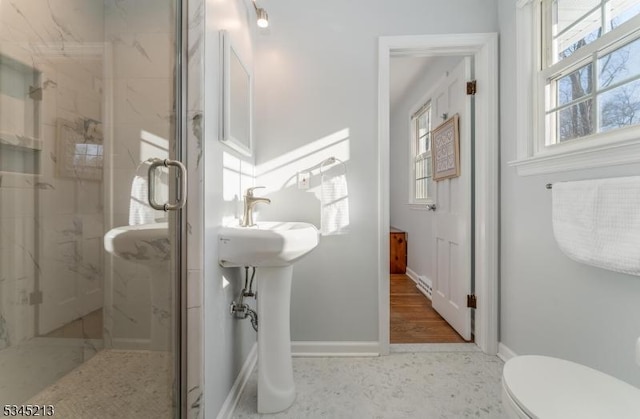 bathroom featuring a marble finish shower, baseboards, and toilet