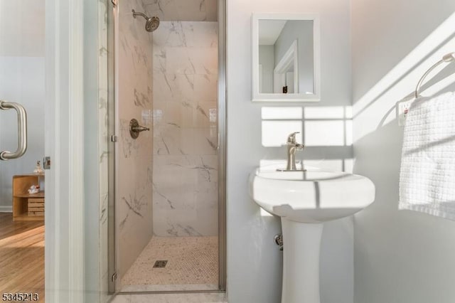 bathroom featuring a marble finish shower and wood finished floors