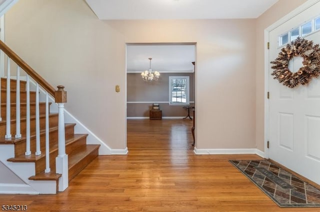 foyer entrance featuring light wood-type flooring, baseboards, stairs, and a chandelier