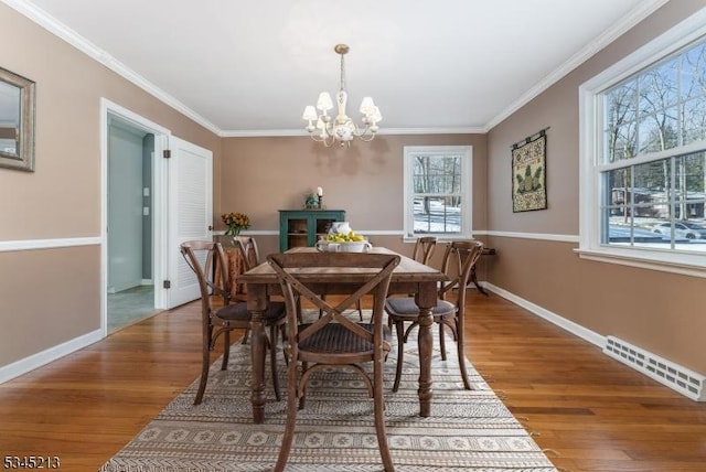 dining space with a chandelier, crown molding, wood finished floors, and baseboards