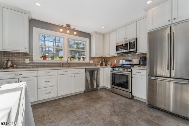 kitchen featuring stainless steel appliances, a sink, backsplash, white cabinetry, and light countertops