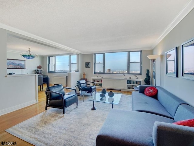 living area featuring baseboards, light wood finished floors, and ornamental molding